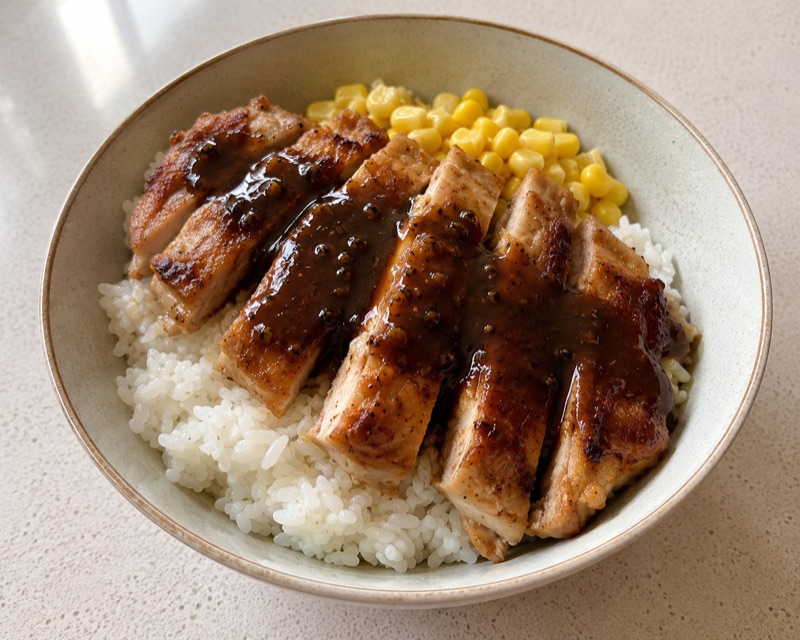 White rice bowl with skillet chicken, corn, and black pepper sauce